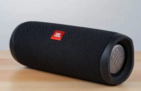 Czarny głośnik JBL na drewnianym blacie. Dowiedz się, jak podłączyć głośnik JBL do komputera przez USB, aby cieszyć się lepszym dźwiękiem.