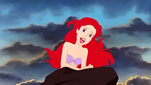 Ariel z "Małej Syrenki" na skale, z burzowymi chmurami w tle. W jej oczach widać marzenie o śpiewaniu w świecie ludzi, jak w pięknych **disney piosenki**.